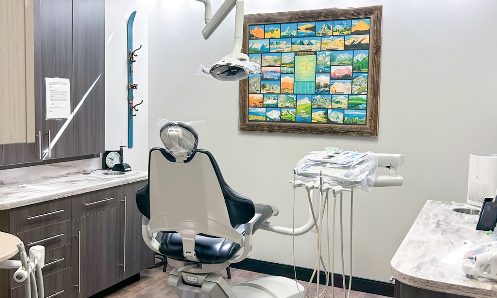 Modern dental treatment room with patient chair, overhead light, and Colorado Fourteeners artwork on the wall