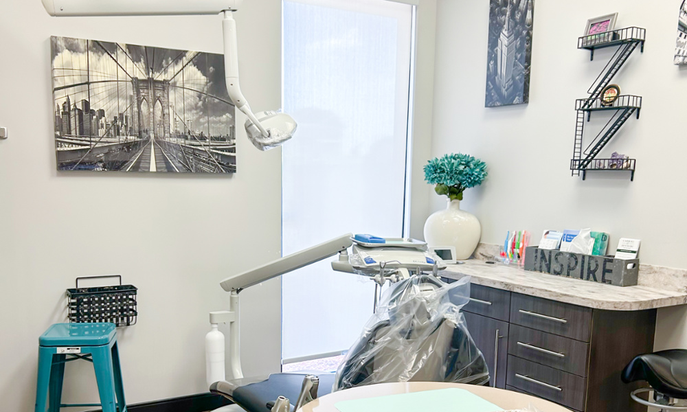 Modern dental treatment room with New York-themed decor, dental chair, overhead light, and marble countertop